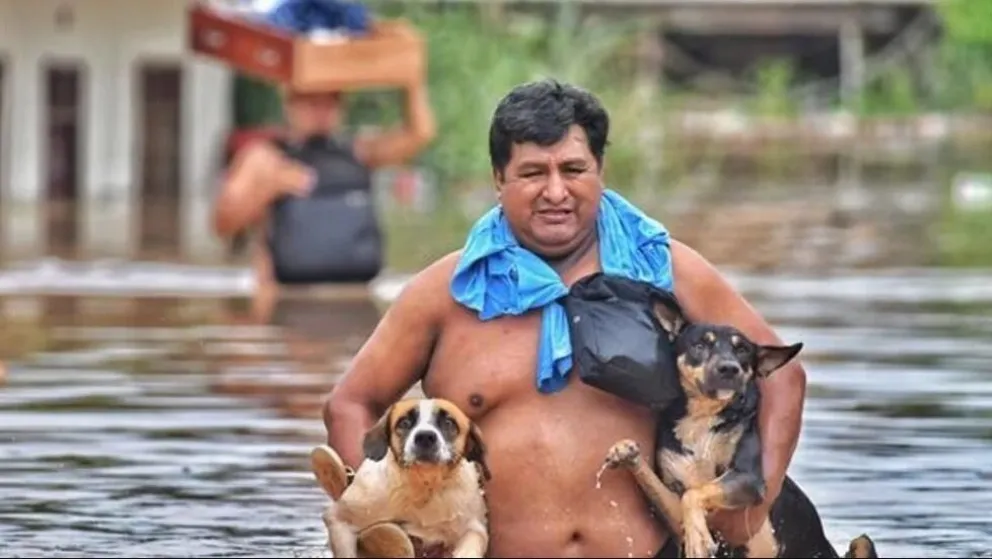 Un hombre con sus mascotas después de que el río Acre aumentara su caudal en Cobija. Foto: Efe