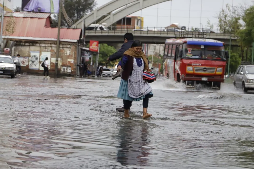Personas y vehículos atraviesan las zonas inundadas. FOTO: APG