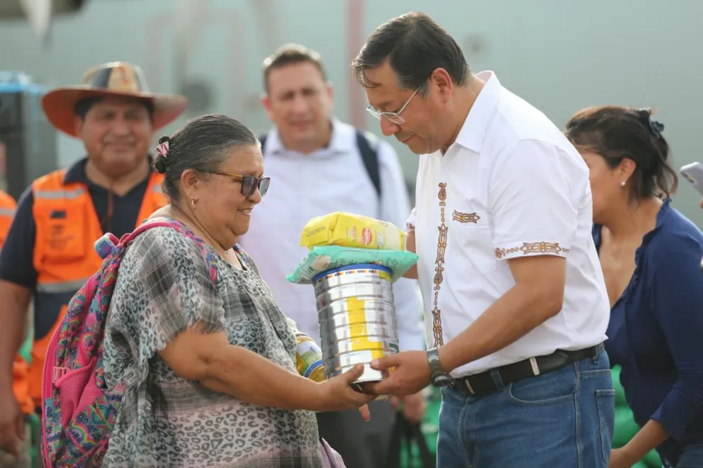 El presidente Luis Arce entrega alimentos a una de las damnificadas por las inundaciones. Foto: ABI