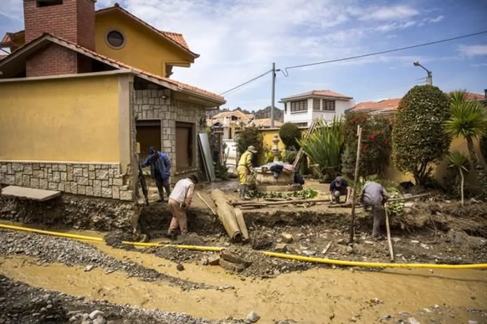 Varias personas trabajan en la entrada de una vivienda, afectada por escombros tras una inundación, en La Paz. (EFE)