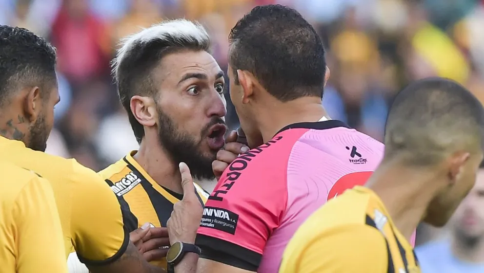 Luciano Ursino frente a frente con el árbitro Gery Vargas le reclama por un cobro. El mediocampista tuvo una buena tarde en el clásico. Foto: APG