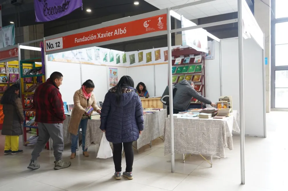 Dos visitantes ven la oferta en  el estand de la Fundación Xavier Albó.
