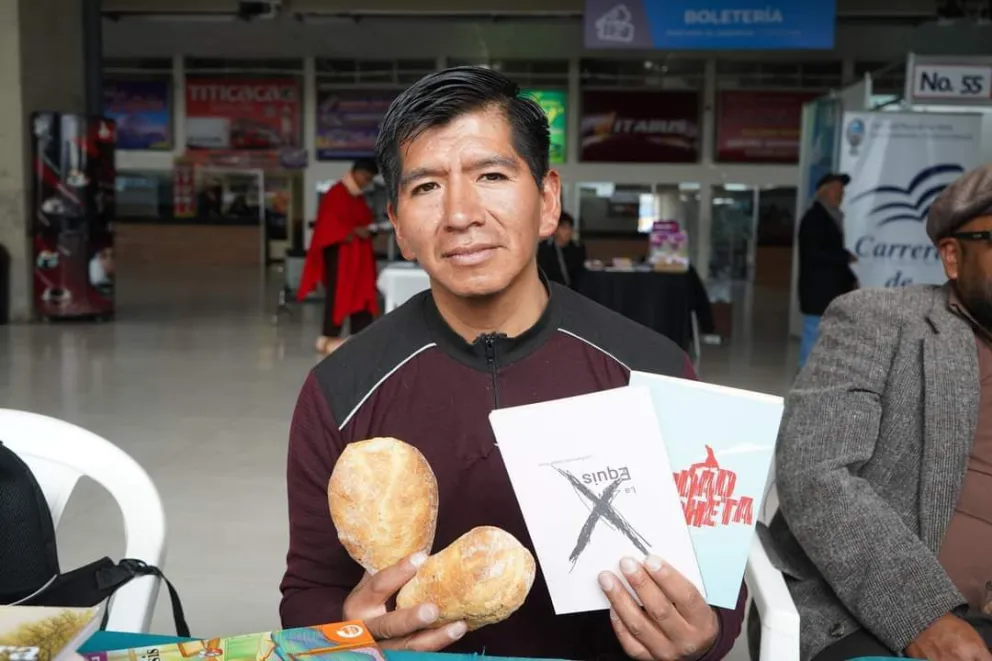 El escritor y panadero Raimundo Quispe Flores muestra sus libros y el pan que regaló en FILEA.  Foto CDLLP