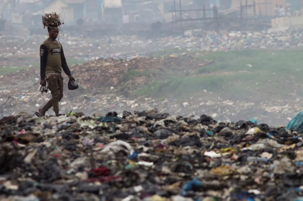Un hombre transporta cables sobre su cabeza en un vertedero de Ghana, considerado el mayor vertedero de basura electrónica de África. Foto: EFE