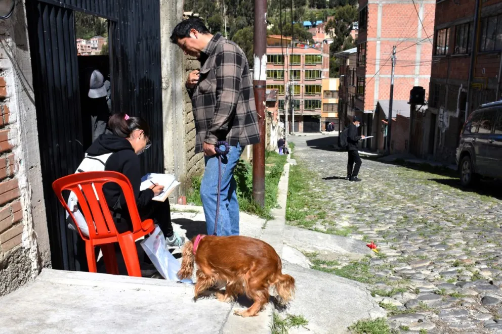 Una joven voluntaria registra los datos de una familia, sentada en una silla. Foto: Mirna Echave