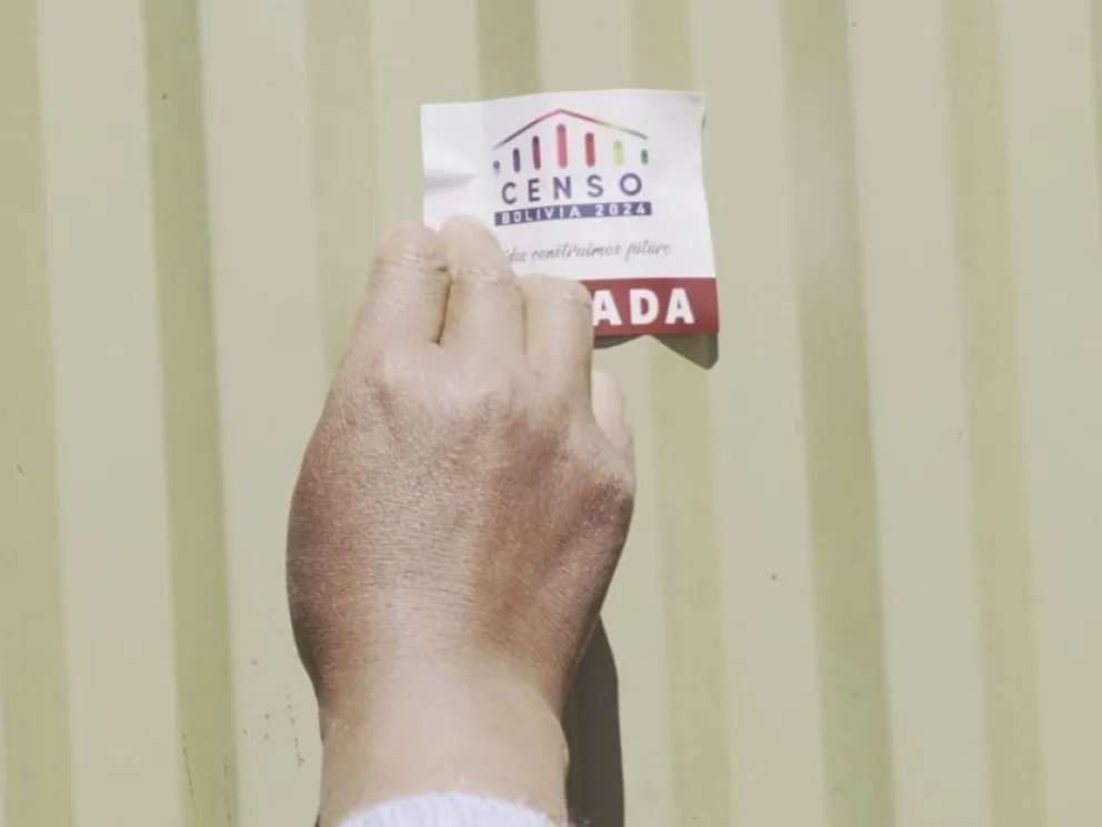 Una censadora pega el sticker en una puerta. Foto APG