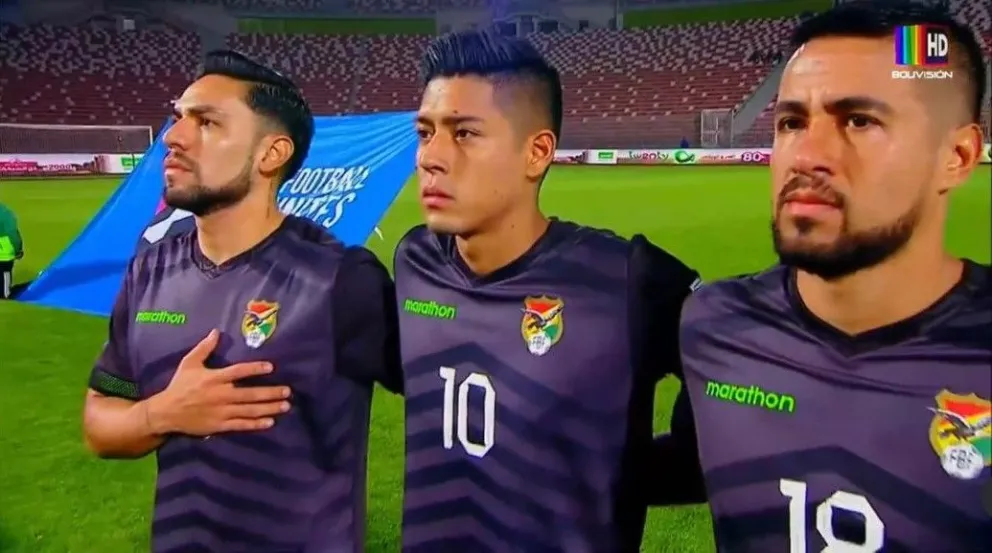 Carmelo Algarañaz (izq). Ramiro Vaca y Rodrigo Ramallo esperan la música correcta del Himno Nacional en la ceremonia previa del partido entre Bolivia y Andorra. Captura Bolivisión. 