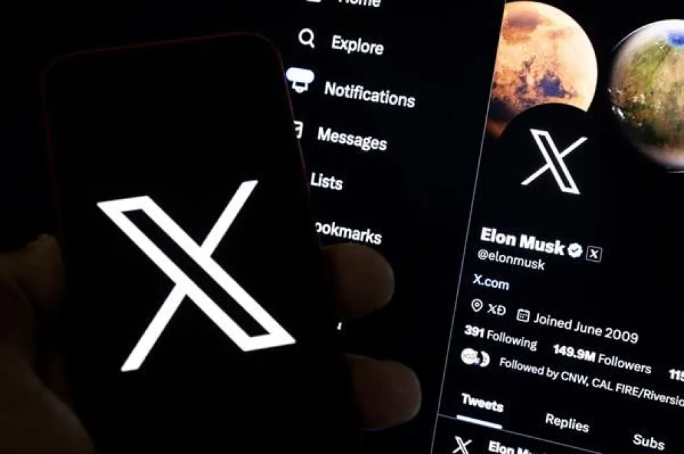 Una imagen ilustrativa muestra a un usuario sosteniendo un teléfono móvil con el logo 'X' frente a la página de Elon Musk. Foto: EFE/EPA/Etienne Laurent
