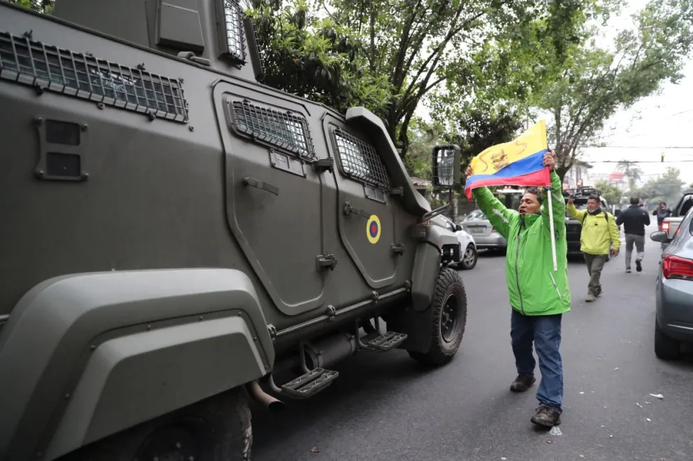 Un hombre exhibe una bandera mientras pasa un vehículo blindado donde se traslada al exvicepresidente ecuatoriano Jorge Glas. Foto: EFE