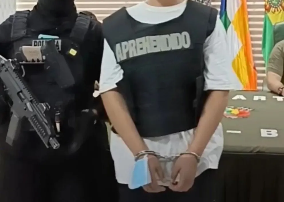 Un policía escolta a la acusada de parricidio en Santa Cruz.   FOTO: ABI