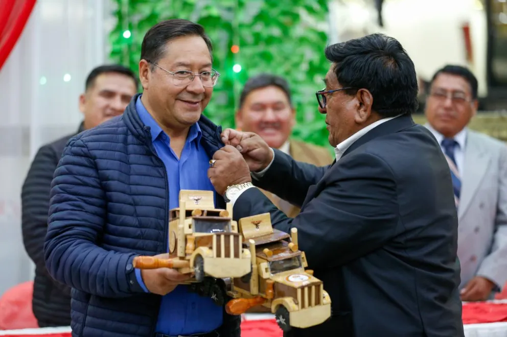 El principal dirigente de la Confederación de Choferes de Bolivia, Lucio Gómez, entrega una matraca hecha en madera al presidente Luis Arce. Foto: Comunicación Presidencial