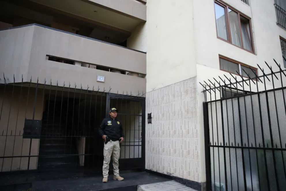 Un policía mientras resguarda el ingreso de la vivienda de Nicanor Boluarte en Lima. Foto: EFE