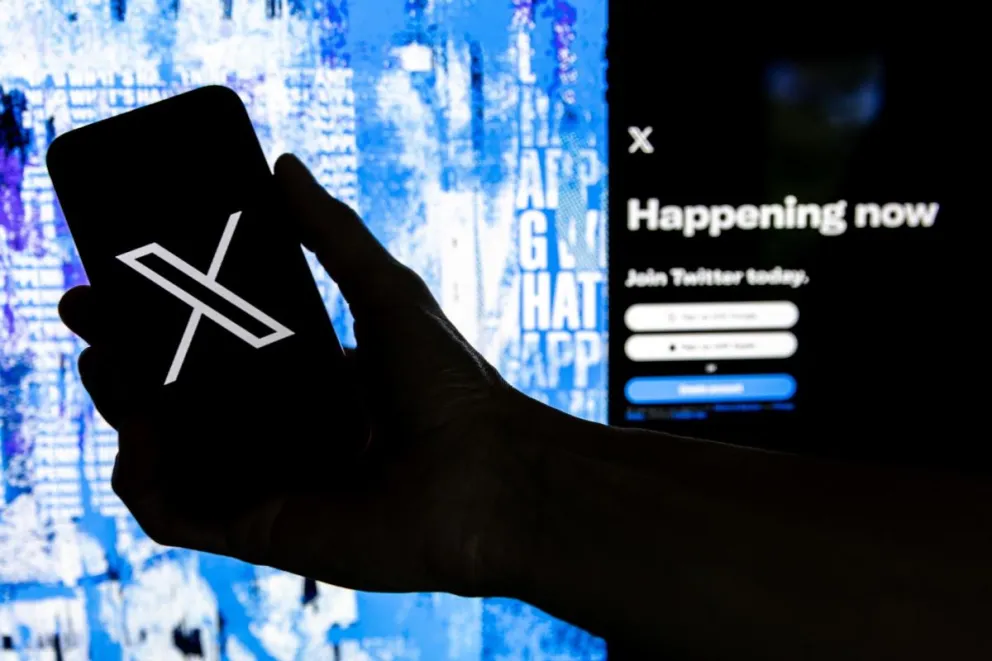 Un usuario sostiene un teléfono móvil con el logotipo X. Foto: EFE