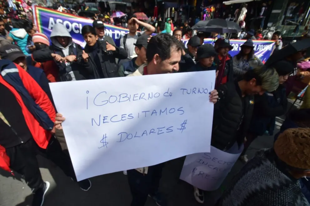 Gremiales marchan por las calles de la ciudad de La Paz, uno de ellos pide dólares con un cartel en la mano. Foto: APG