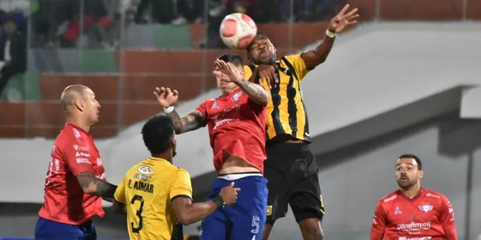 El atigrado Marc Enoumba se eleva más y rechaza de cabeza un ataque de Wilster. Foto: APG 