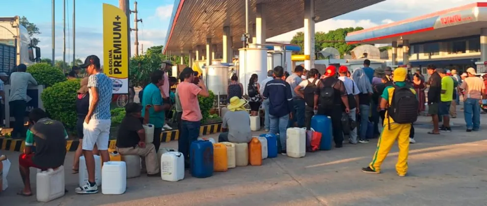 Varias personas hacen fila en un surtidor para comprar combustible en bidones. Foto: Unitel.