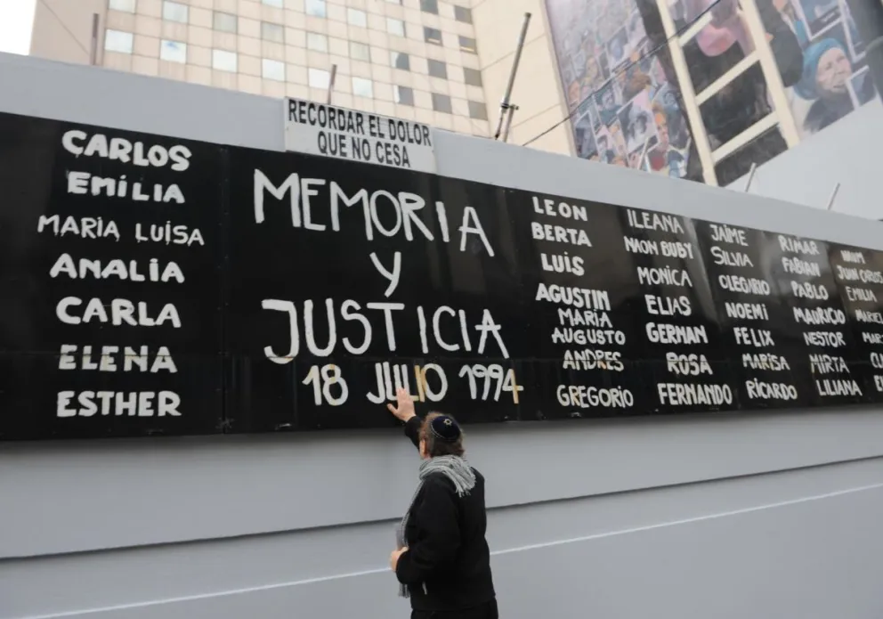Fotografía de archivo de un hombre tocando un cartel con nombres de víctimas durante un acto conmemorativo por los 25 años del atentado contra la mutual judía AMIA, en Buenos Aires. Foto: EFE