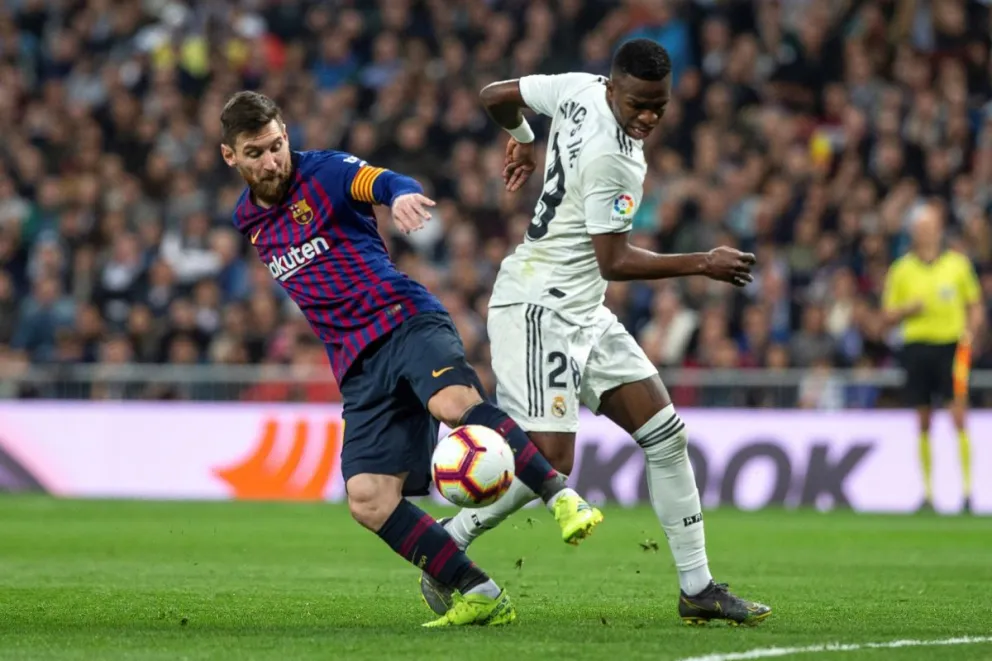 Fotografía de archivo, tomada en marzo de 2019, en la que se registró a Lionel Messi (i), al actuar para el FC Barcelona, al diputar un balón con Vinicius Jr, delantero estrella del Real Madrid, durante un Clásico del fútbol español. Foto: EFE