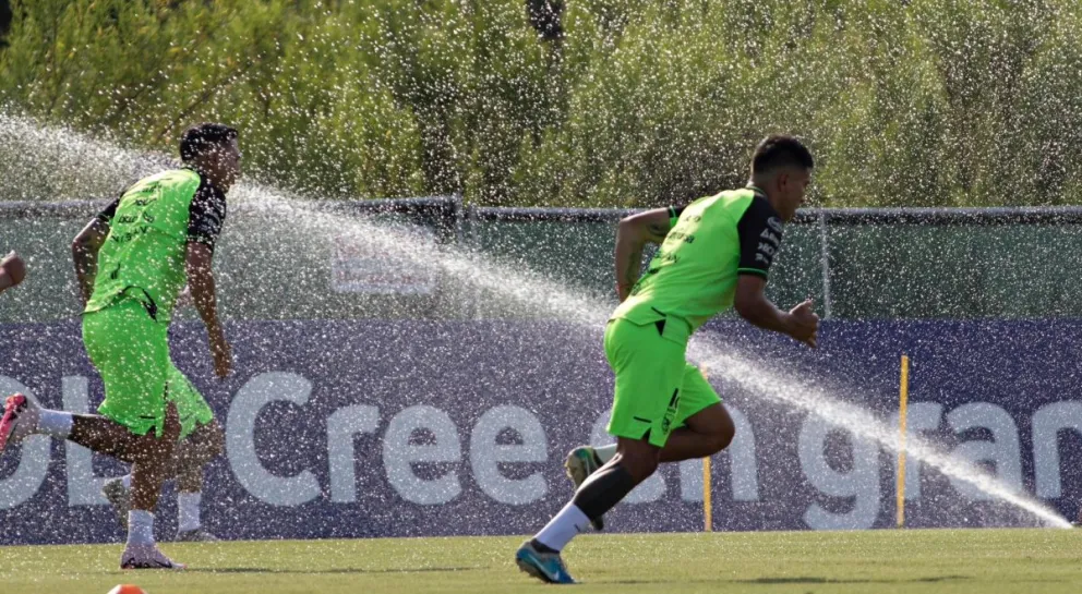 Dos jugadores de la selección cumplen una rutina de trabajo mientras se riega el campo de juego. Foto: Patricio Crooker, APG