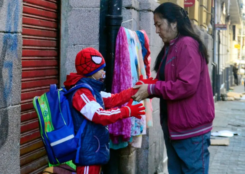 Una madre coloca guantes a su hijo. Foto: ABI