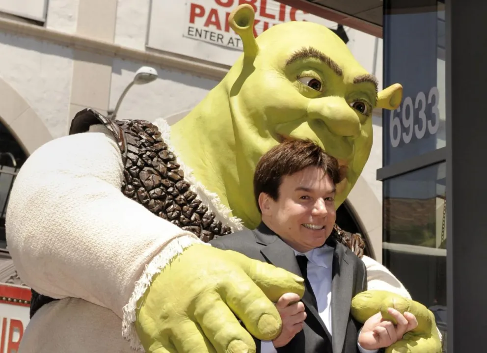 Fotografía de archivo de 2010 de una caracterización de Shrek (atrás), la estrella de la famosa saga homónima, y el actor que le de la voz, Mike Myers (frente), mientras reciben la estrella número 2.408 en el paseo de la fama de Hollywood. Foto: EFE