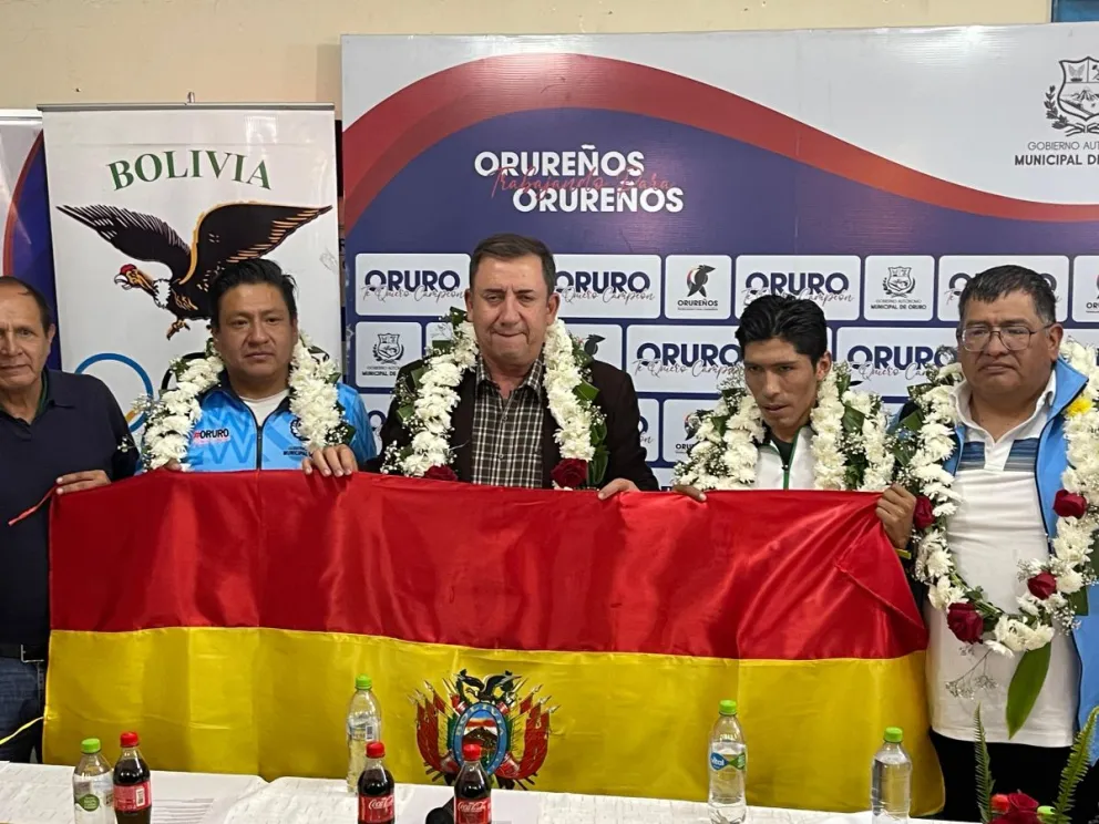 Arze con Garibay (centro) y otras autoridades sostienen la bandera nacional. Foto: COB.