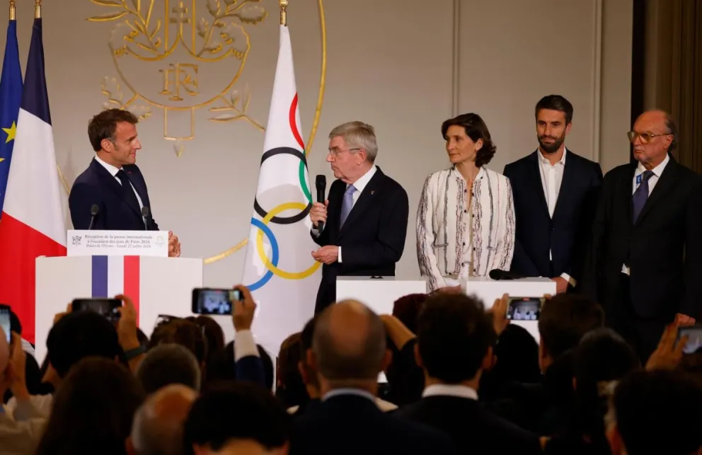 El presidente del COI Thomas Bach, micrófono en mano, se dirige al presidente de Francia Emmanuel Macron. Foto: EFE