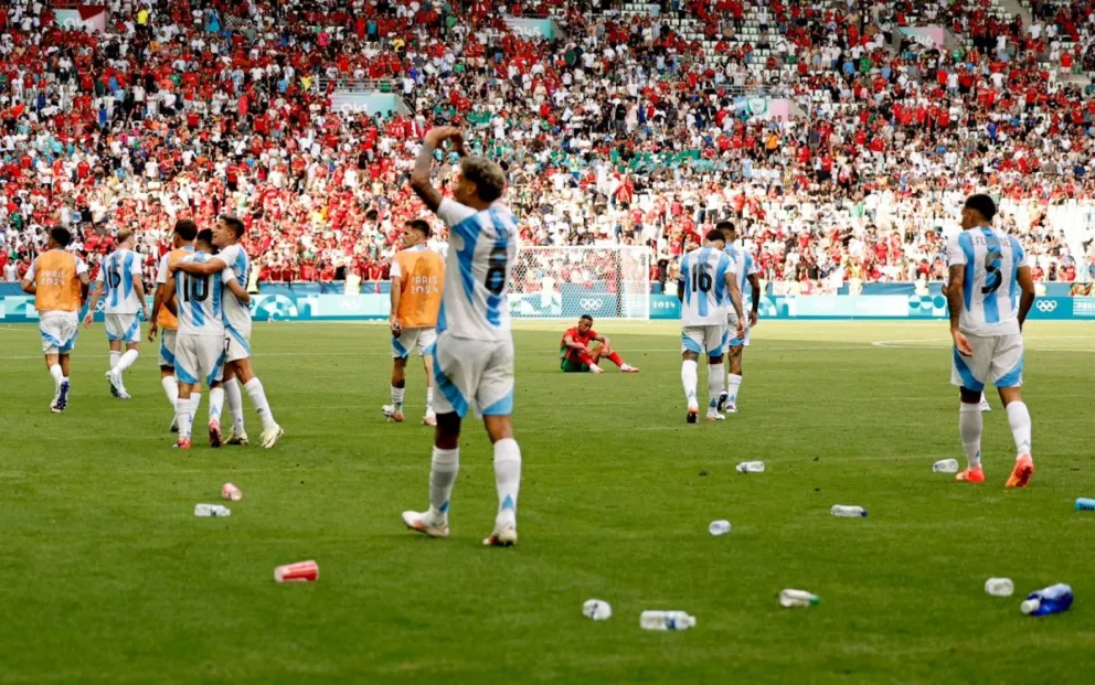 Los jugadores argentinos celebran y observan las graderías, mientras se ve el campo de juego con envases de plástico. (Foto Mediotiempo)