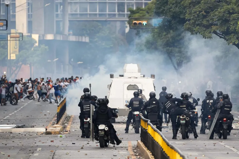 Agentes de seguridad enfrentan a manifestantes en Caracas. Foto: EFE