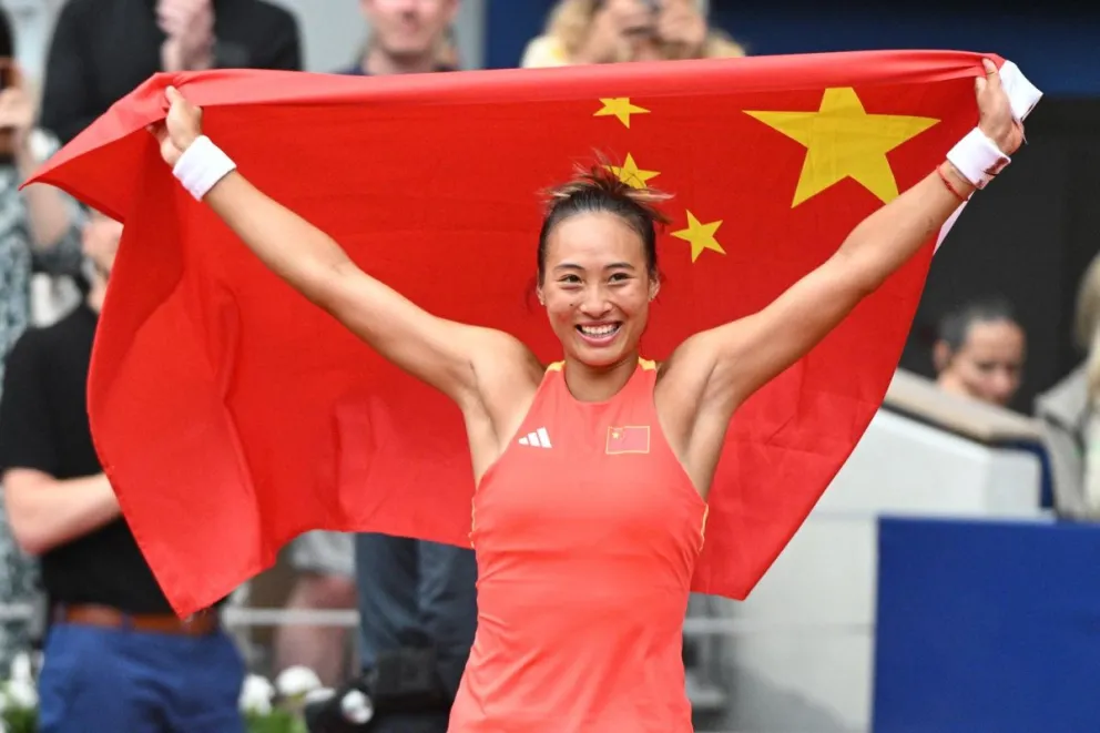 La china Qinwen Zeng levanta la bandera de su país tras el oro olímpico. Foto: EFE.