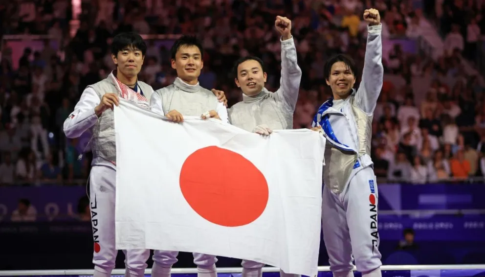 El equipo masculino nipón con su bandera tras ganar el oro en florete. Foto: EFE.