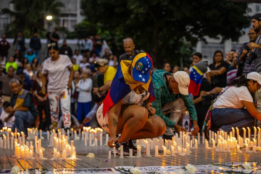 Personas prendes velas durante una vigilia por los presos políticos en Venezuela. Foto: EFE