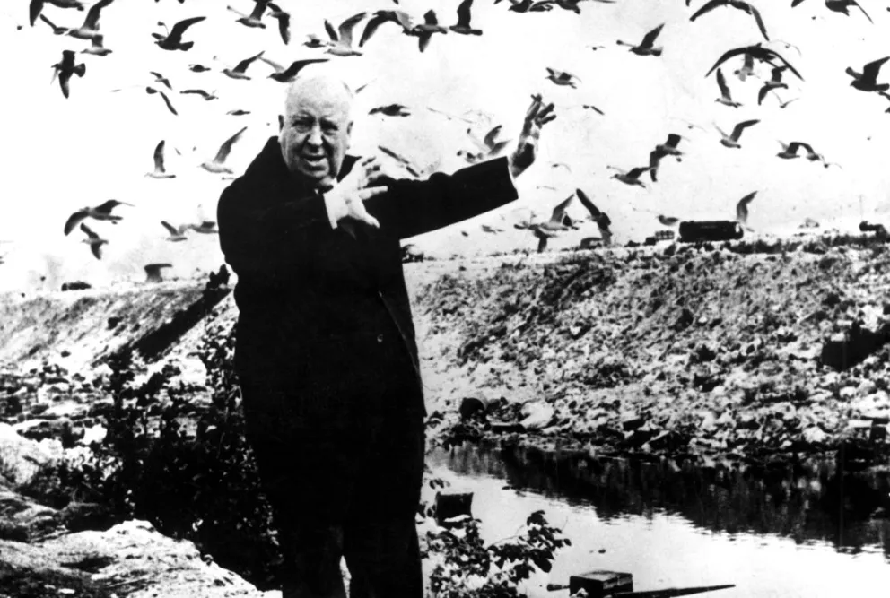 El director de cine británico Alfred Hitchcock se acerca a un par de gaviotas durante el rodaje de "The Birds", en 1963. Foto: EFE
