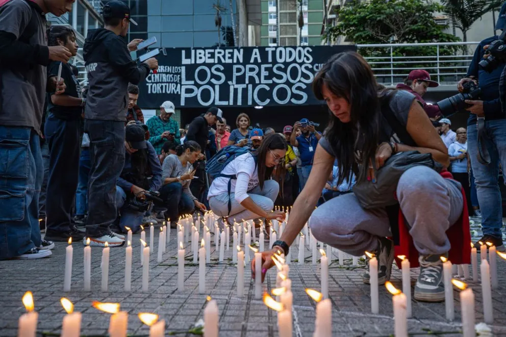 Personas prenden velas en una vigilia por los presos políticos, convocada por la oposición en Caracas. Foto: EFE