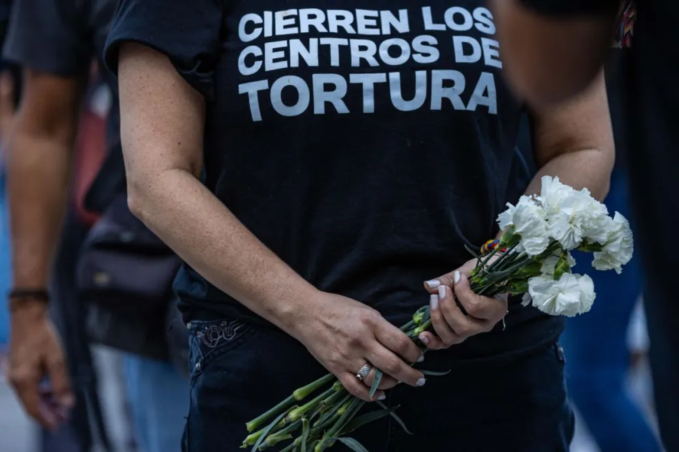 Una mujer que sostiene flores durante la gran vigilia nacional por los presos políticos en Caracas. Foto: EFE