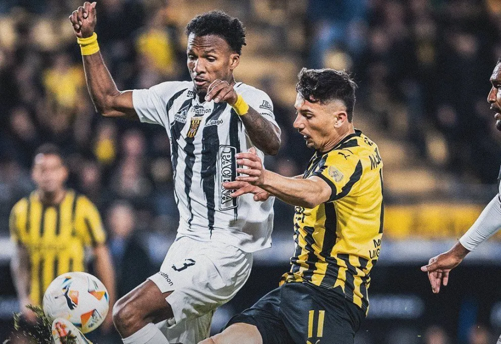 Aimar intenta despejar el balón ante la presencia de un jugador de Peñarol. Foto: Peñarol