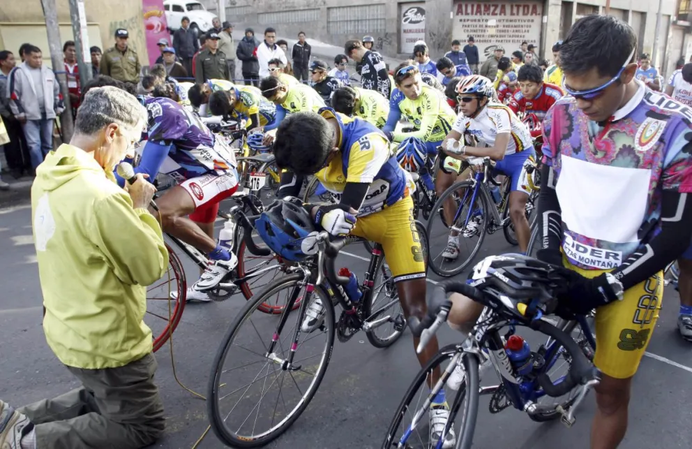 El Padre Eduardo Pérez eleva una oración y bendice a los ciclistas en la previa de una etapa de la Vuelta a Bolivia. Foto: APG