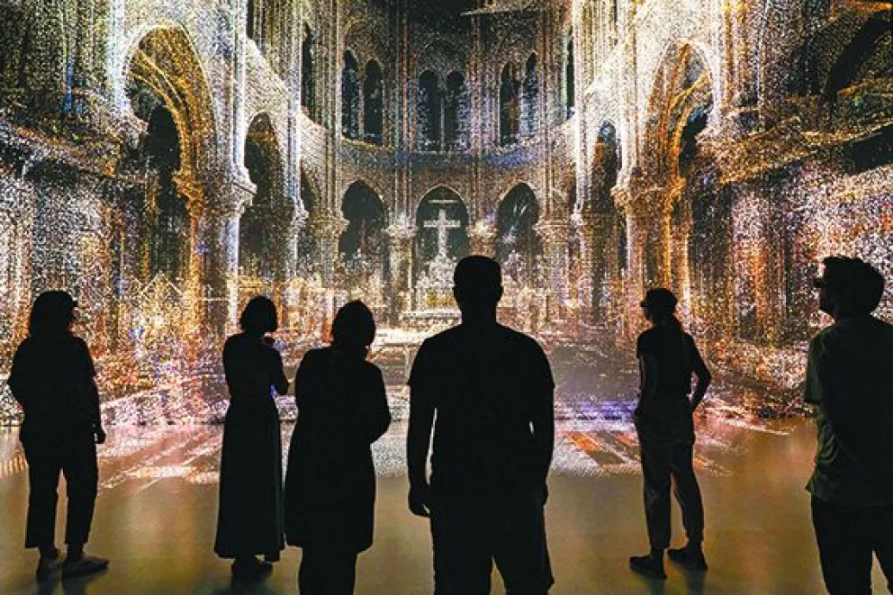 Personas observan cómo la tecnología revive una de las catedrales más importantes de Europa, incendiada hace cinco años. FOTO: EFE