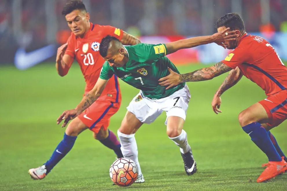 Juan Carlos Arce intenta eludir a dos jugadores de la selección chilena en el partido de 2016. Foto: LT