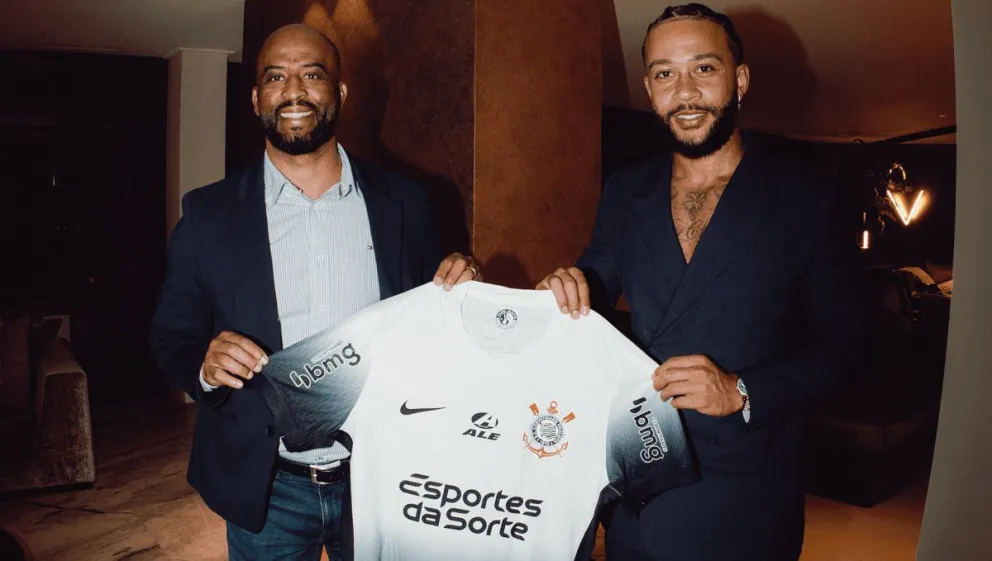 Memphis Depay (der.) posa sosteniendo la camiseta de su nuevo club. 