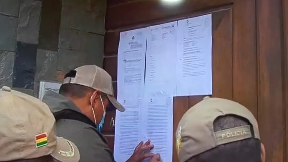 Efectivos de la Felcc pegan la notificación en el domicilio de Evo Morales. Foto: DTV 