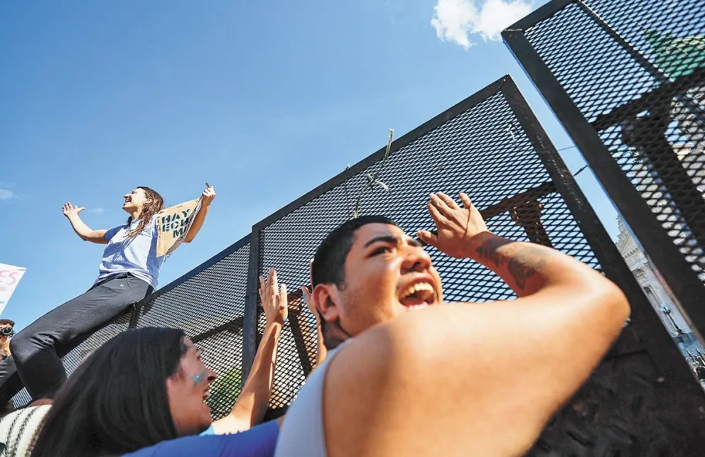 Personas intentan derribar la seguridad a las afueras del Congreso, durante una manifestación estudiantil. Foto: EFE 