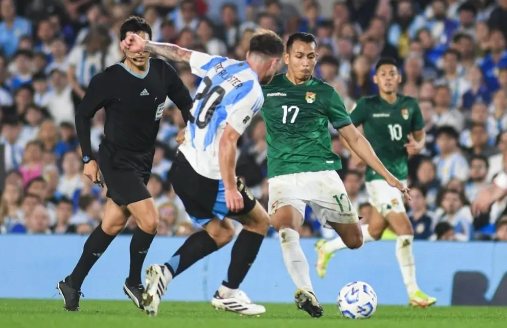 Roberto Carlos Fernández se apresta a mandar un centro marcado por Alexis Mac Allister. Foto: APG