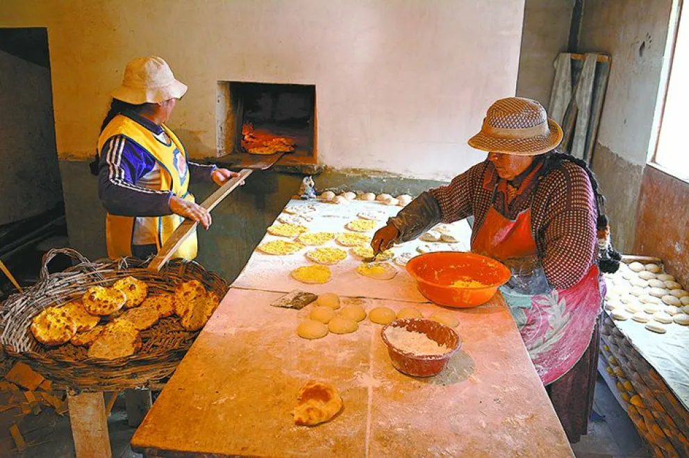Victoria, en el proceso de horneado, mientras su madre coloca el queso sobre la masa. FOTO: Jorge Soruco / Visión 360