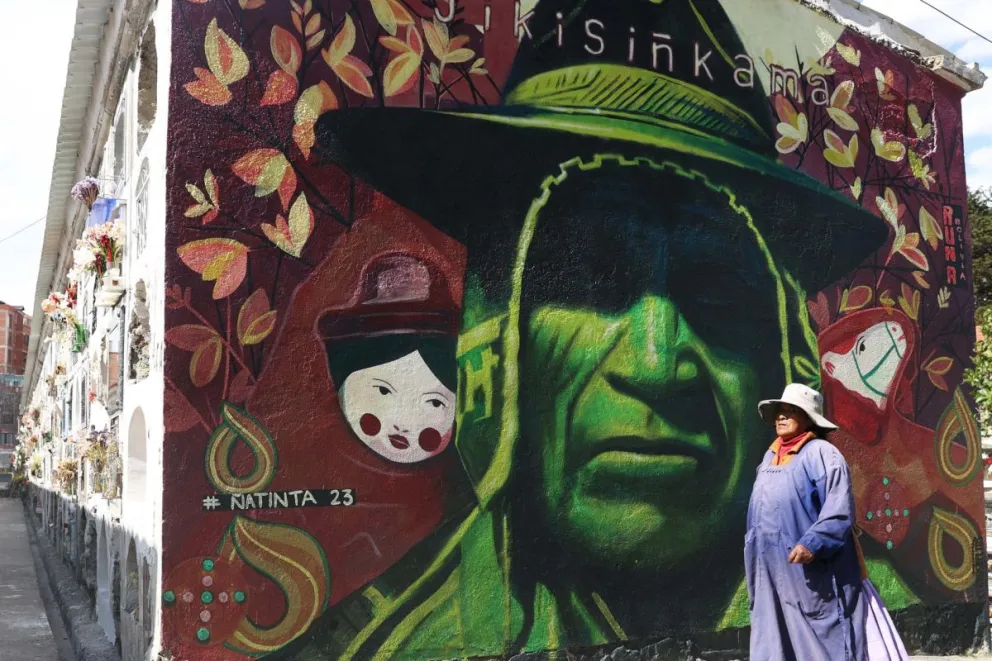 Una mujer aymara camina delante de un mural perteneciente al proyecto "Ñatinta", en los pasillos del cementerio general, este miércoles, en La Paz (Bolivia). Foto: EFE