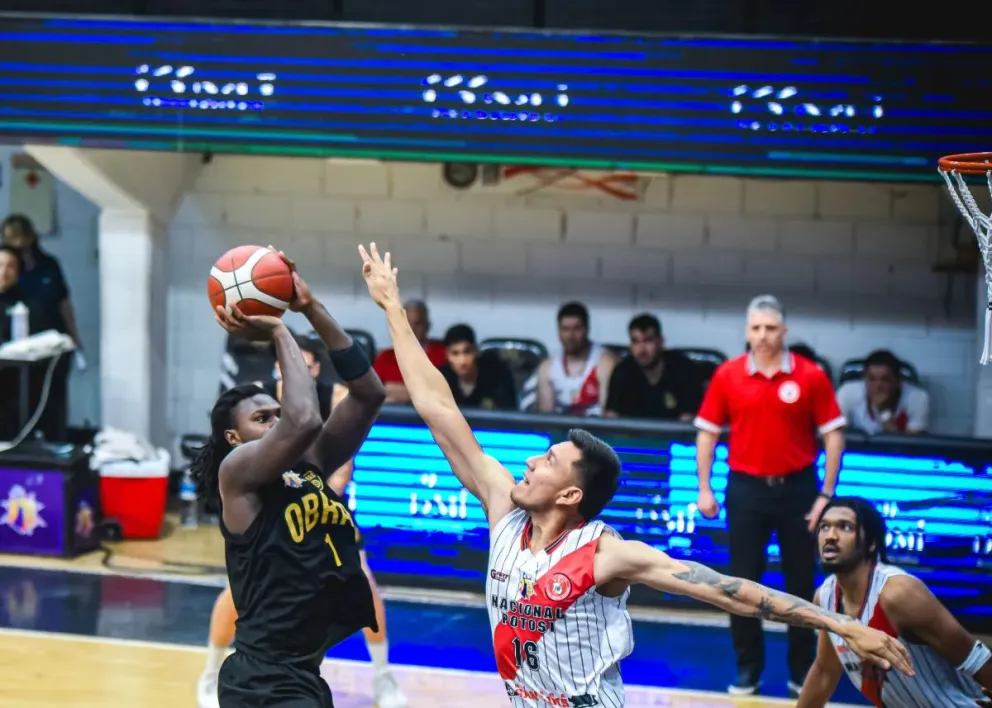 Un jugador de Nacional (de blanco) bloquea el lanzamiento de su rival de Obras Sanitarias. Foto: FIBA América.