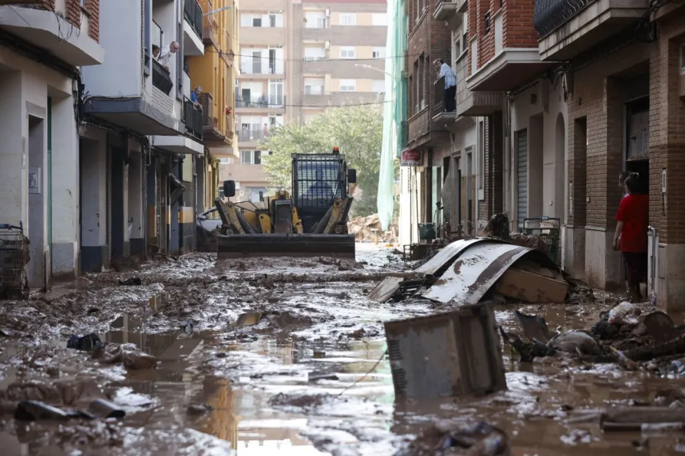 Una máquina escavadora retira el lodo acumulado en las calles tras las intensas lluvias, este jueves en Catarroja, una de las localidades afectadas. Foto: EFE