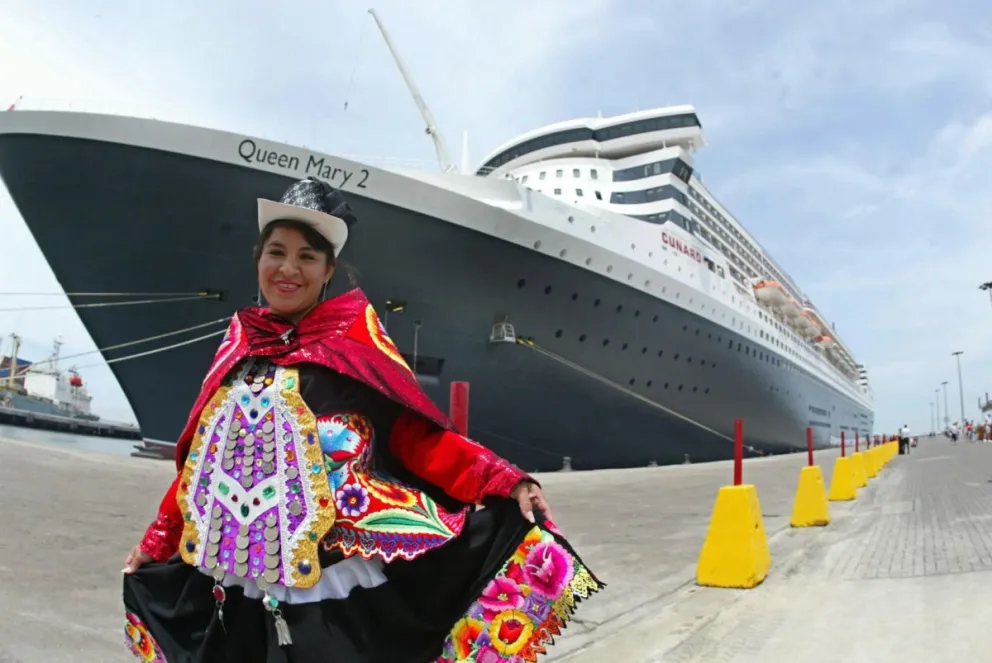 Fotografía de archivo que muestra a una vendedora de souvenirs posando al frente de un crucero transatlántico en el puerto del Callao (Perú). Foto: EFE