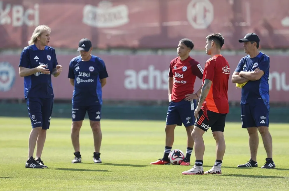 Ricardo Gareca (izq.) conversa con dos jugadores de la selección y los miembros de su cuerpo técnico. Foto: FFC