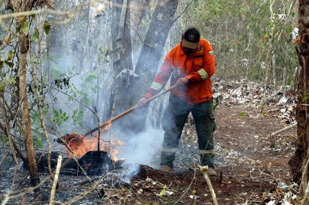 Un bombero que mitiga los restos de un incendio en San Miguelito (Bolivia). Foto: EFE
